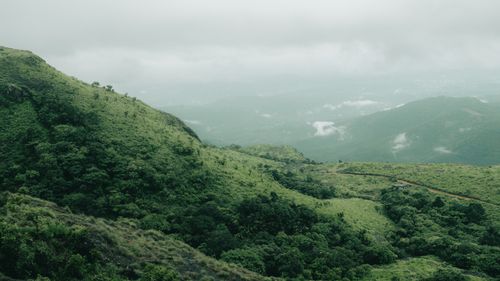 Free A scenic view of verdant hills shrouded in clouds, evoking tranquility and nature's beauty. Stock Photo