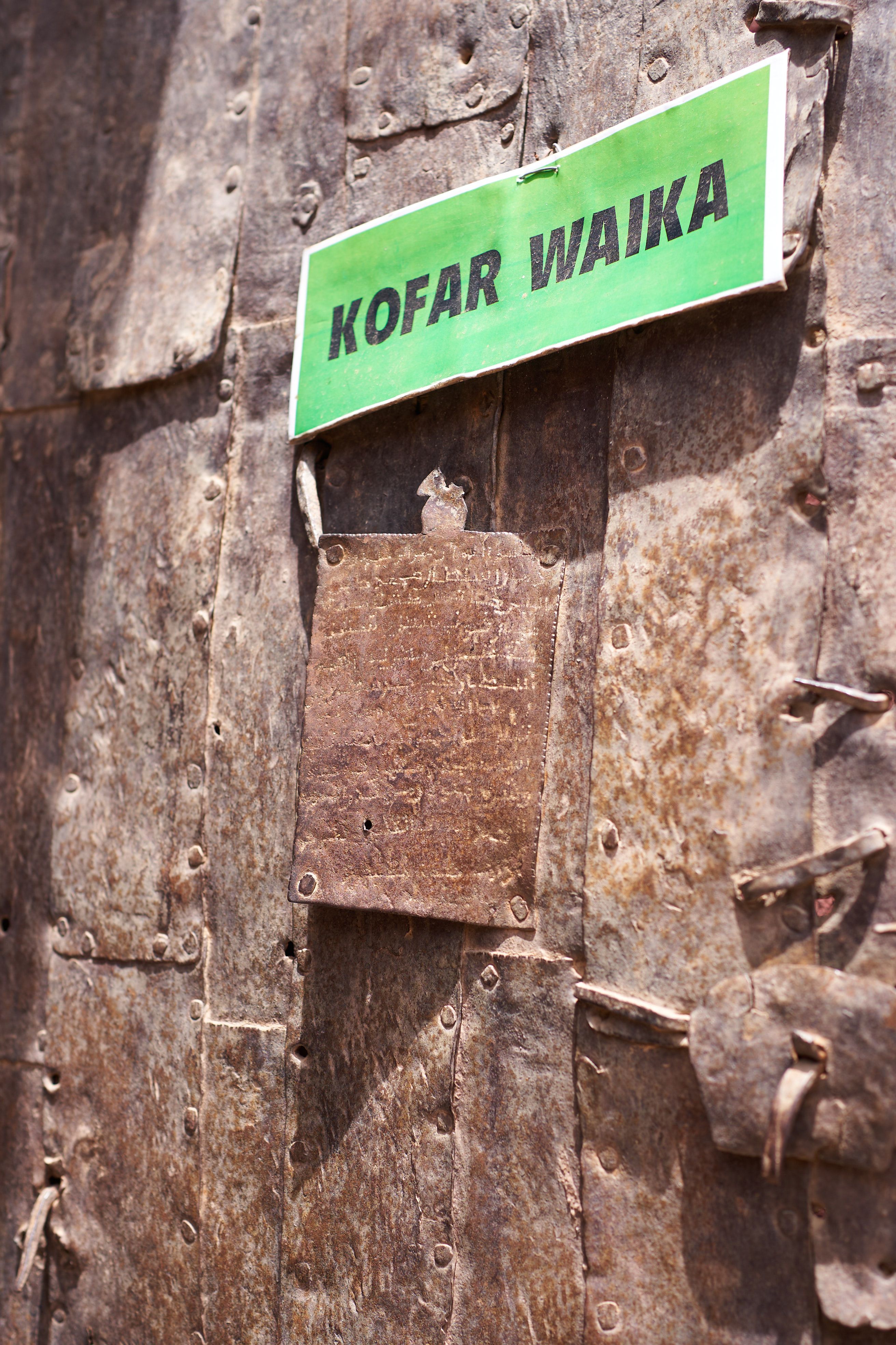 Kofar Waika Sign on Rustic Metal Door