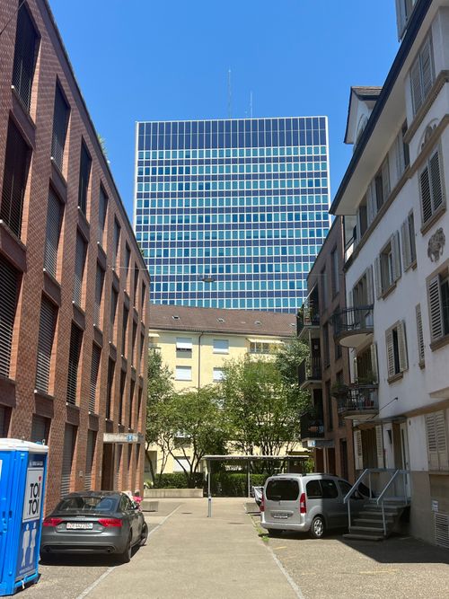 Free View of urban street flanked by brick residential buildings leading to a blue skyscraper. Stock Photo