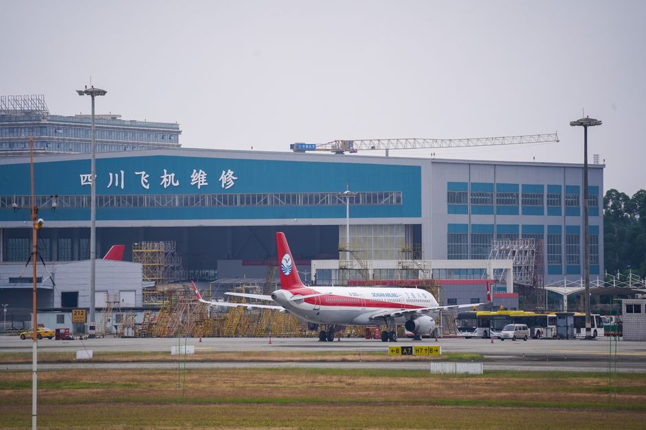 Airplane parked in front of Sichuan aircraft maintenance hangar, day view.