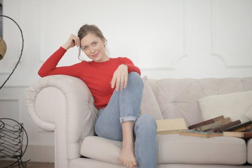 紅色長袖襯衫和藍色牛仔牛仔褲，坐在沙發上的女人