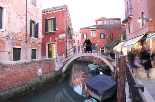 Waterway with old buildings and people on sidewalks in Venice