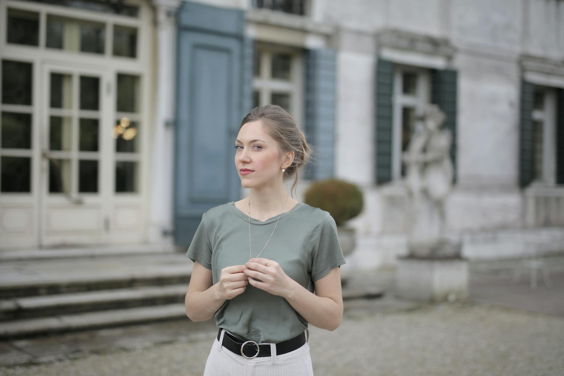 Beautiful young woman standing near old building and looking at camera
