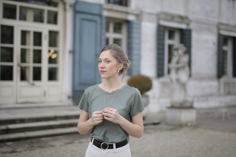 Beautiful Young Woman Standing Near Old Building And Looking At Camera