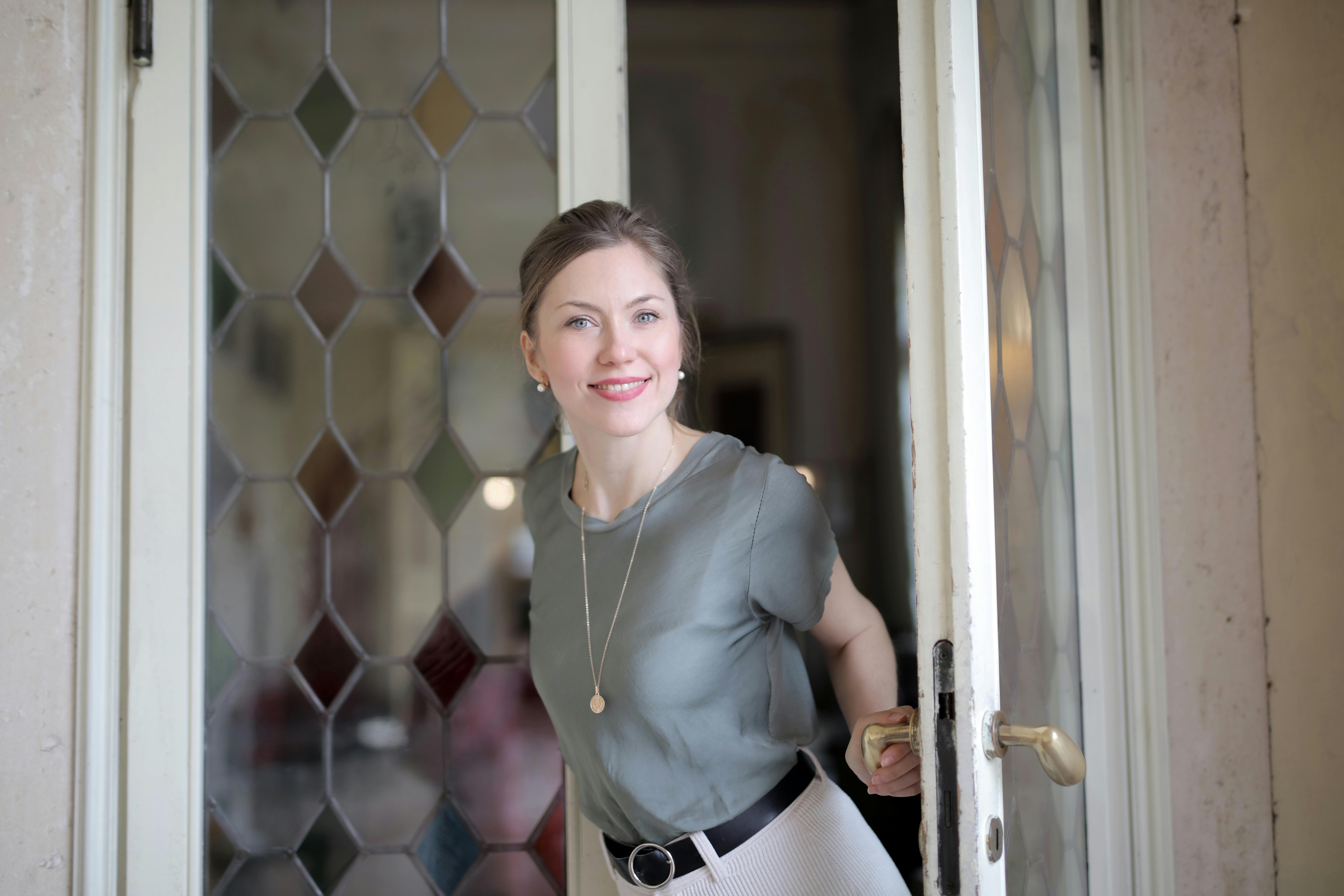 positive young woman entering through stained glass door