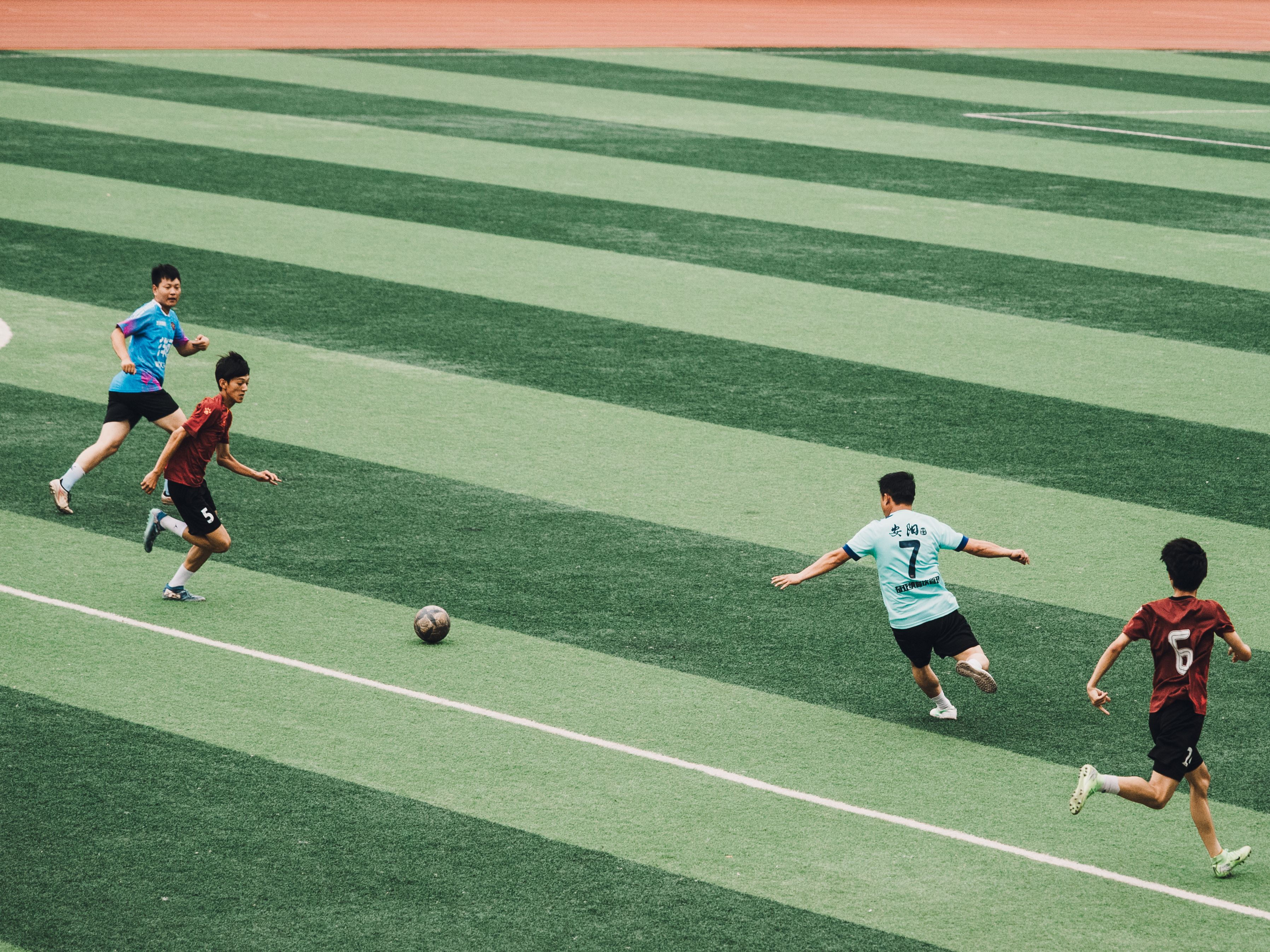 Dynamic soccer match with teenagers playing on a vibrant green field.