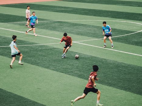 Action shot of teenagers playing soccer on a green sports field.
