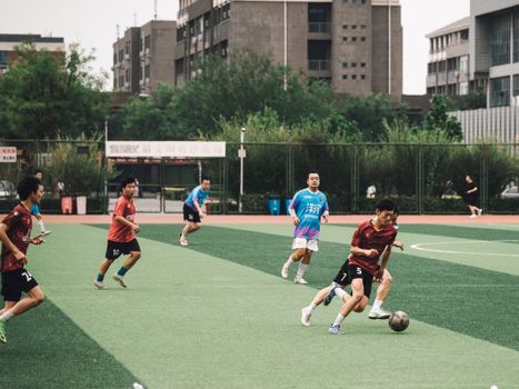 Players engaged in a lively amateur soccer match on an urban outdoor field.