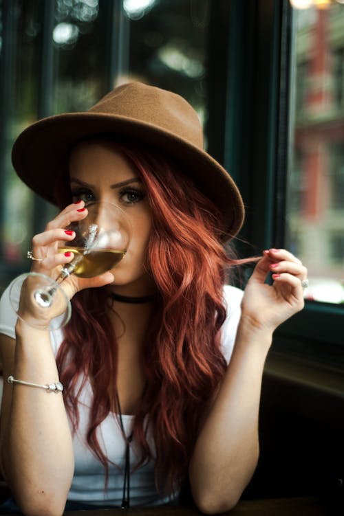 Var에 화이트 와인을 마시는 빨강 머리 여자