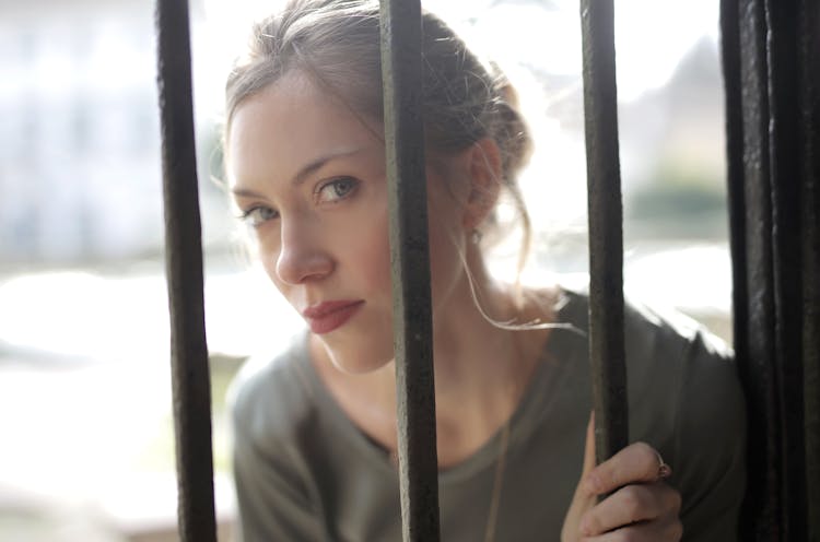 Young Gorgeous Woman Standing Behind Iron Grate