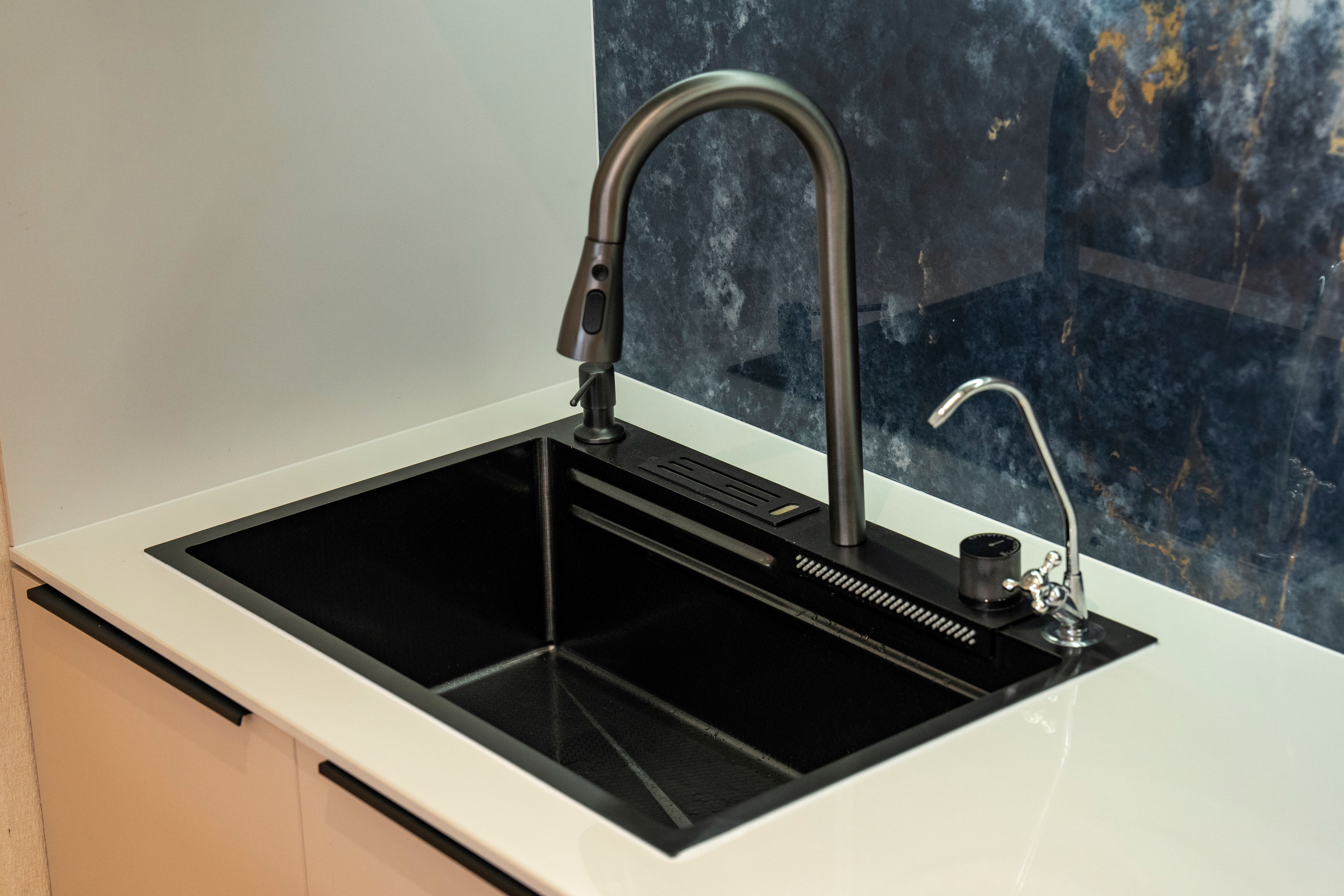 A sleek black kitchen sink with a modern faucet and marble backsplash, ideal for contemporary interiors.