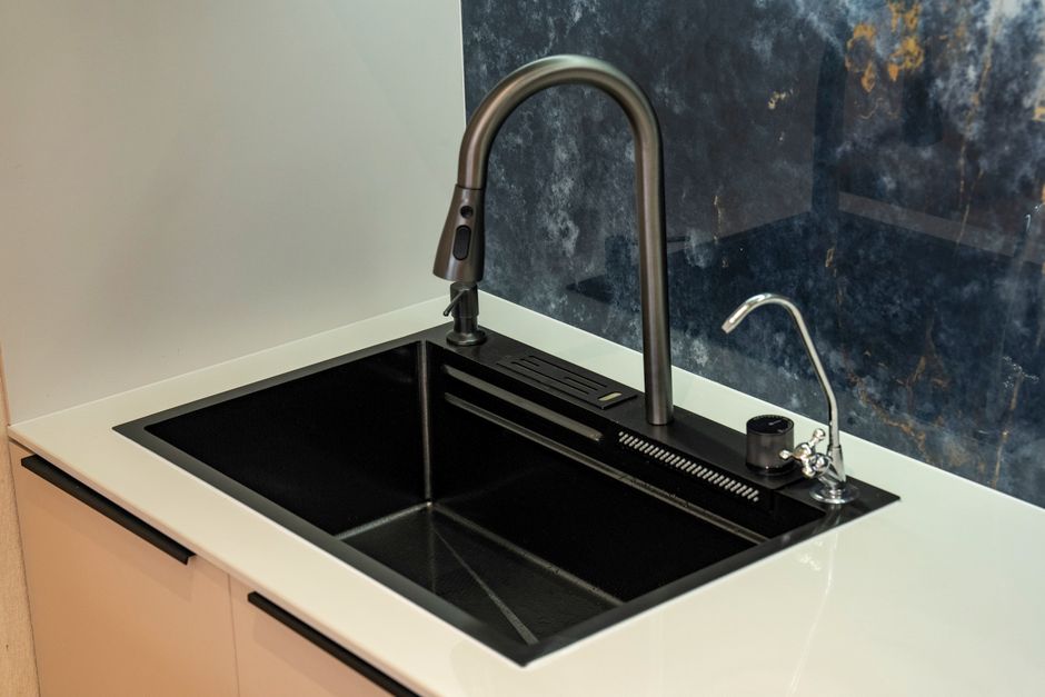 A sleek black kitchen sink with a modern faucet and marble backsplash, ideal for contemporary interiors.