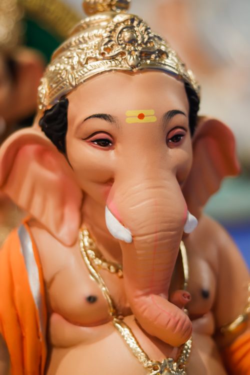 Free Close-up of a beautifully detailed Lord Ganesha idol adorned with ornate gold decorations and vibrant colors, symbolizing wisdom and prosperity. Stock Photo