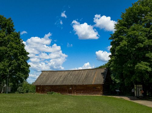 Free Charming wooden structure surrounded by lush greenery and vibrant blue sky, perfect for summer retreat. Stock Photo