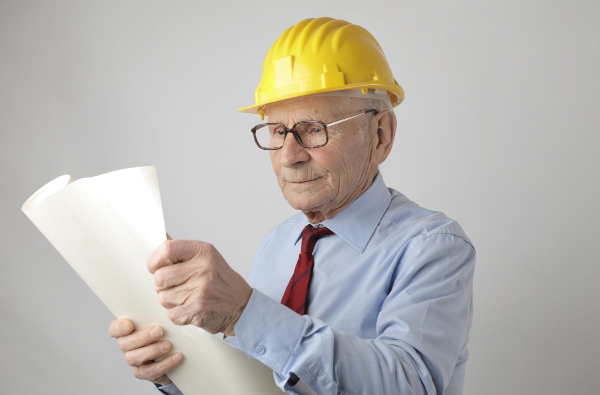 Senior engineer studying a printed blueprint drawing in a studio