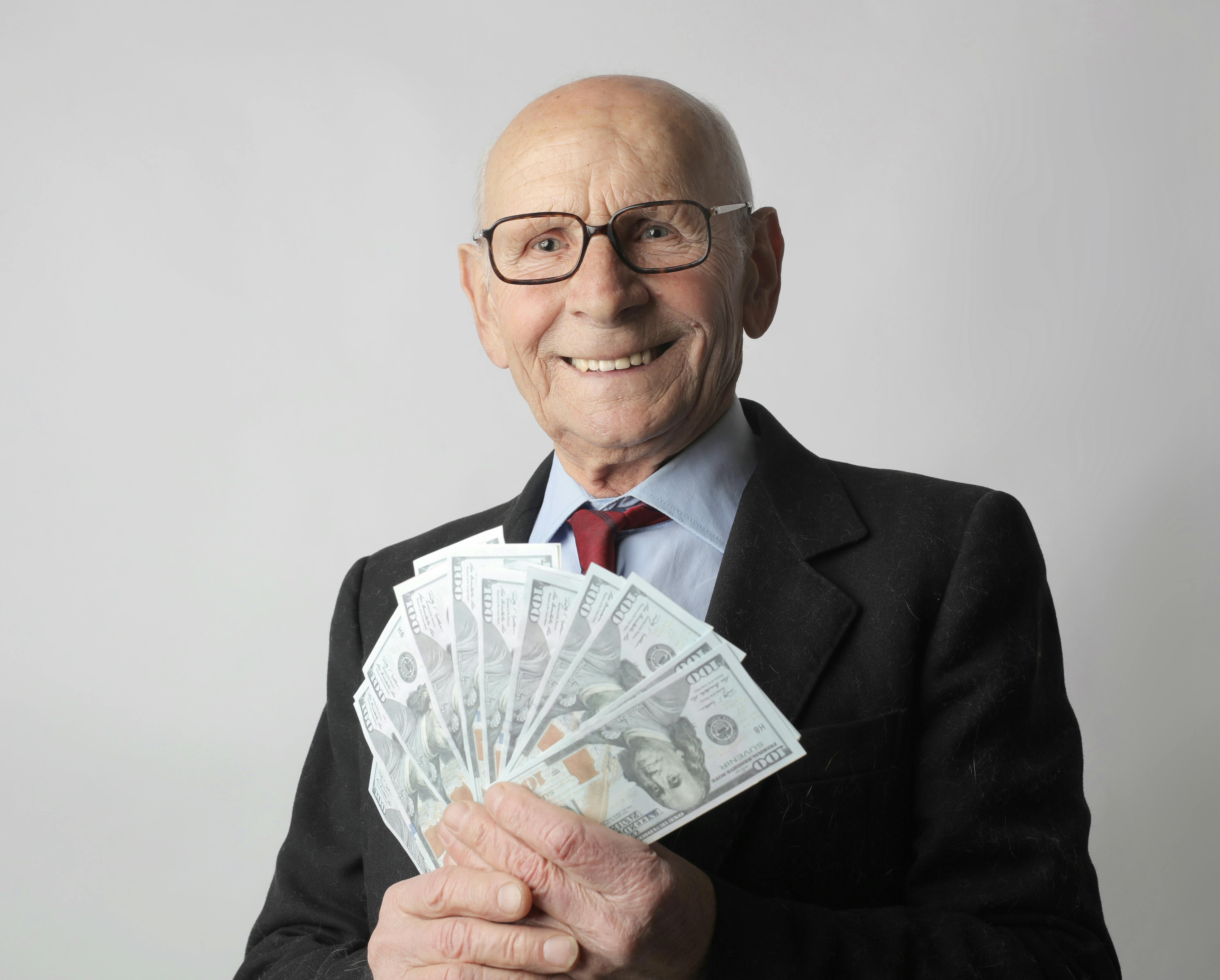 Man in black suit holding dollar bills. | Photo: Pexels