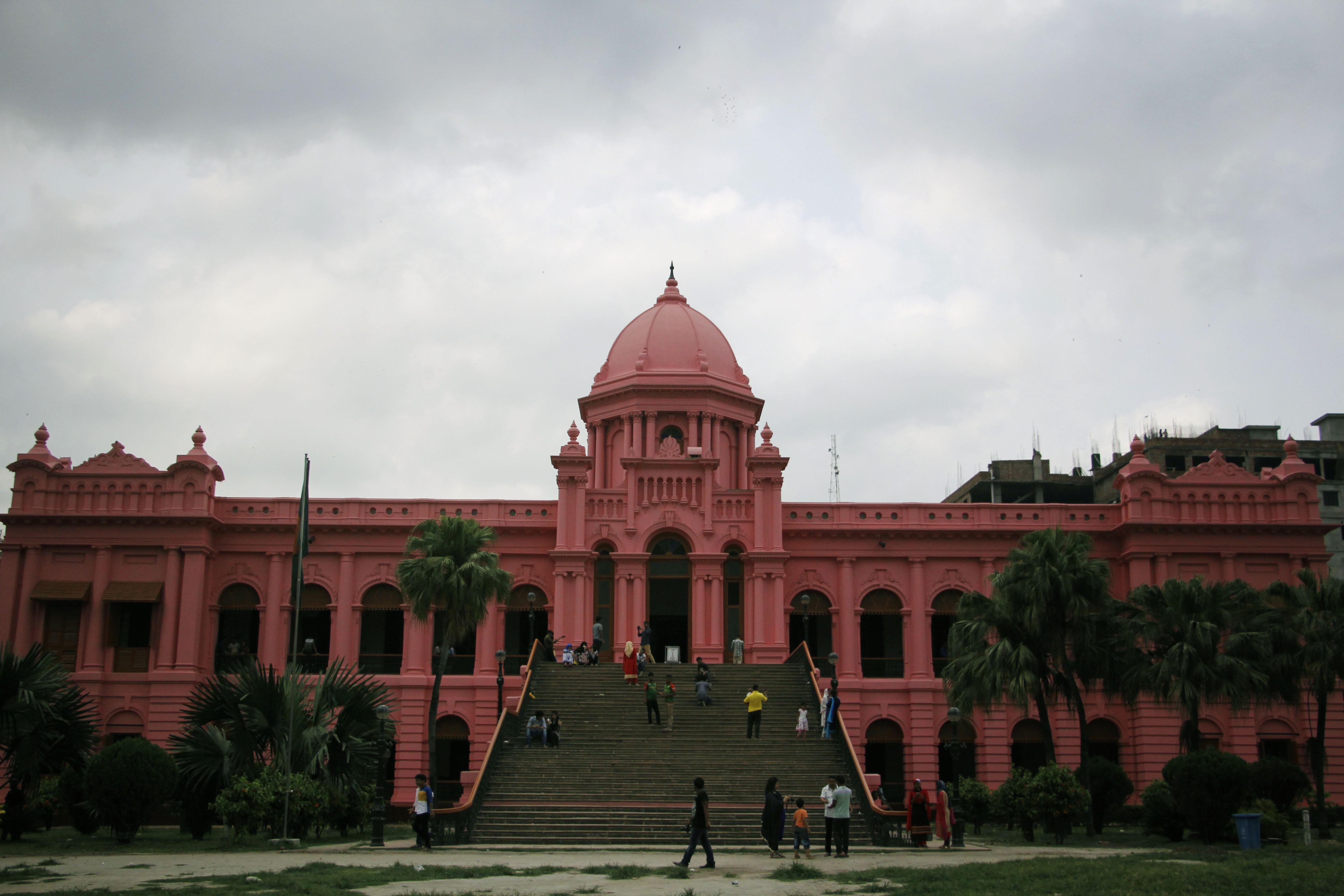 A stunning view of Ahsan Manzil, the iconic pink palace in Dhaka, under a cloudy sky.