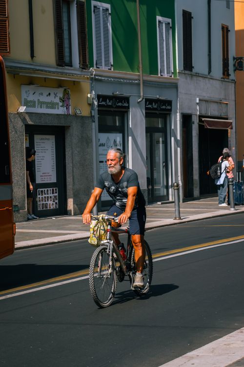Free Man rides a bicycle along a vibrant urban street on a sunny day, embracing an active lifestyle. Stock Photo