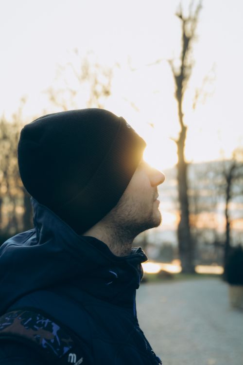 Free A man in a winter jacket and beanie admires a sunset in a park in Wrocław, Poland. Stock Photo