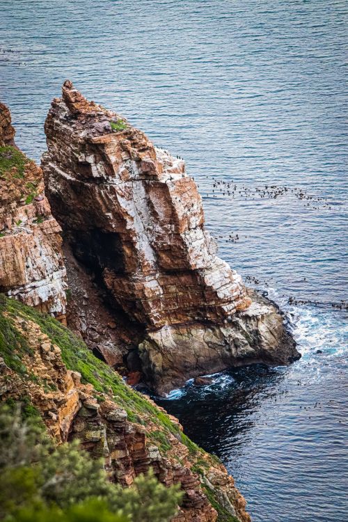 Free A striking coastal cliff with ocean waves crashing below under a clear sky. Stock Photo