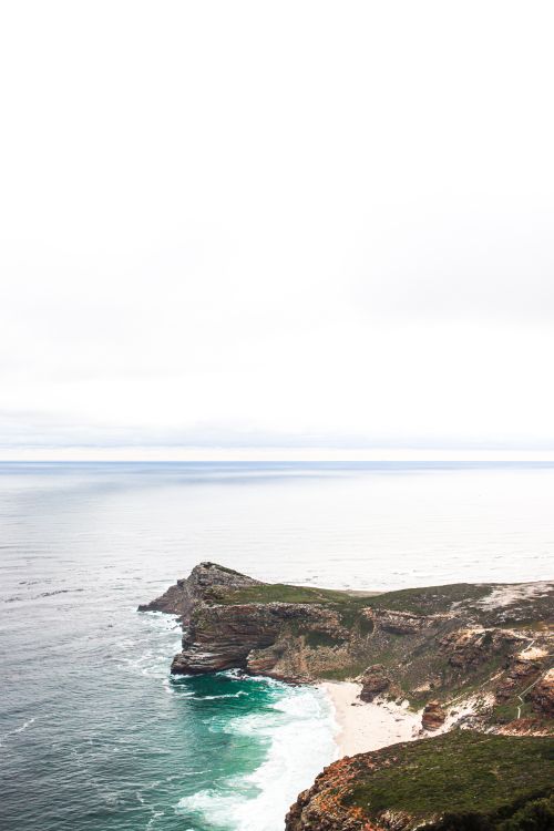 Free A stunning view of the rugged cliffs at Cape Point with azure ocean waves crashing below. Stock Photo