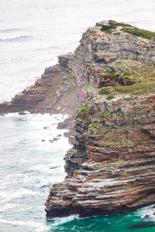 Free Majestic cliffs rise above the ocean waves at Cape Point, offering a breathtaking natural landscape. Stock Photo