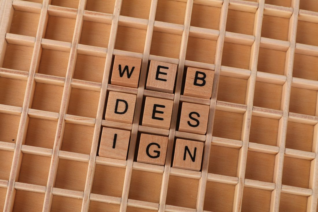 Holzbuchstaben legen das Wort Webdesign – die richtige Website-Basis wählen.