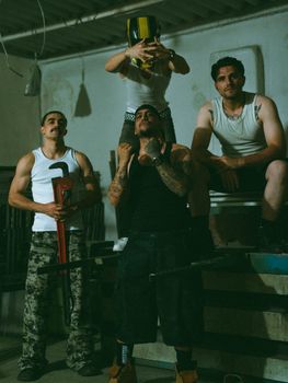 Four men pose in an urban, industrial environment wearing casual attire.