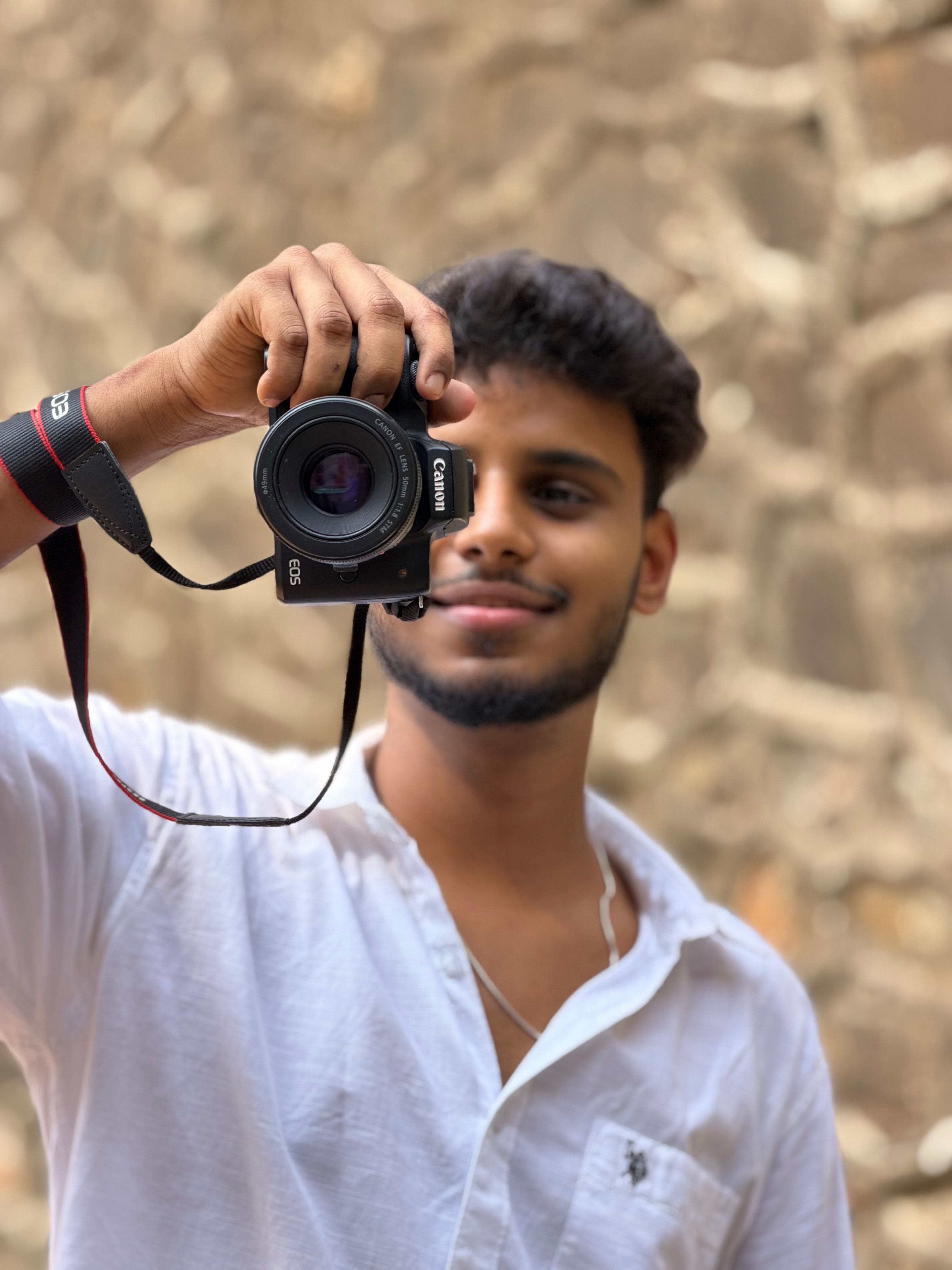 A cheerful adult male holding a camera, ready for a perfect shot outdoors.