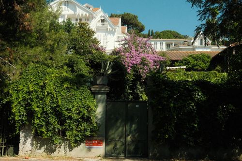 Free Idyllic Mediterranean villa surrounded by lush greenery and vibrant blooms, conveying tranquility. Stock Photo