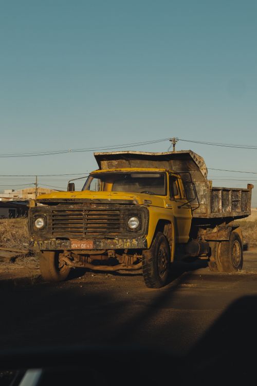 Free A vintage yellow dump truck situated in a sunlit desert landscape, capturing a nostalgic industrial scene. Stock Photo