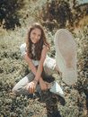 Cheerful woman sitting on grass and raising foot to camera