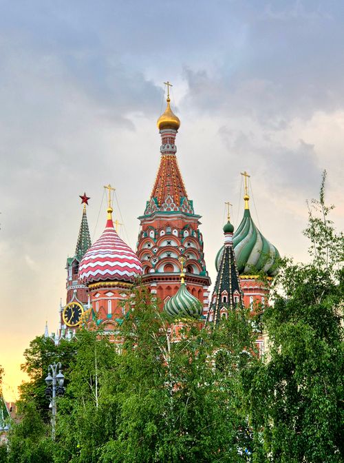 Free View of Saint Basil's Cathedral with colorful domes amidst lush greenery during sunset. Stock Photo