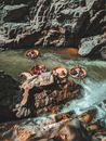 无畏的人从上方沿着岩石悬崖之间快速弯曲的山河，漂浮在典型的越南圆形渔船上