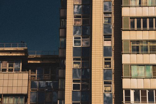 Free Modern high-rise building facade with reflections of clear blue sky in the windows. Stock Photo