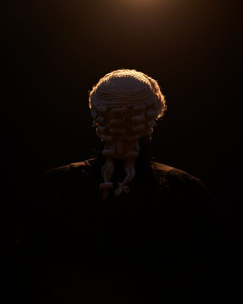 Free Dramatic lighting highlights the judge's silhouette wearing a traditional wig, symbolizing justice. Stock Photo