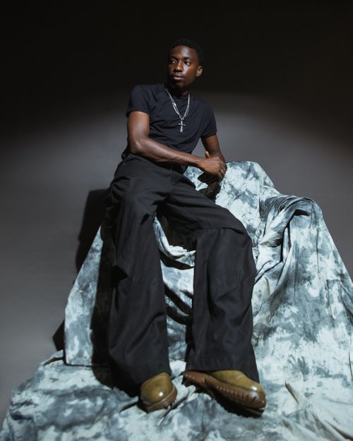 Free Artistic portrait of a man sitting on a draped chair with dramatic lighting. Stock Photo