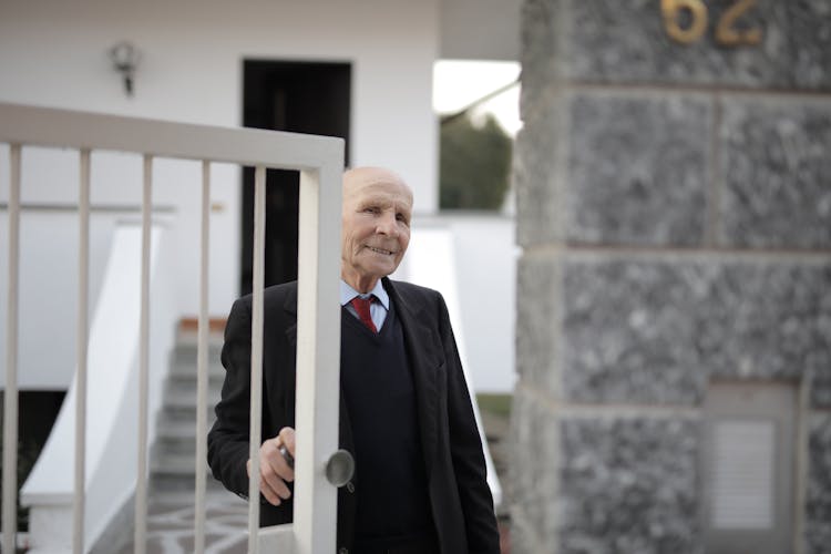 Man In Black Suit Standing Opening The Door