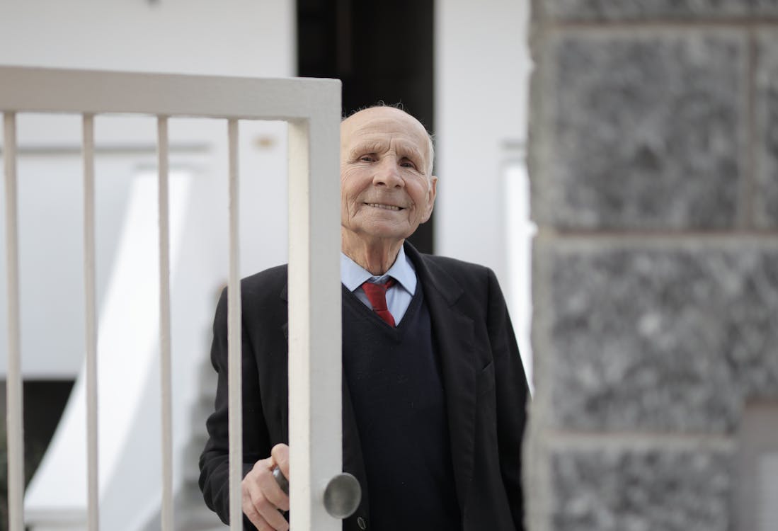 Man in Black Suit Jacket Standing Beside Metal Gate