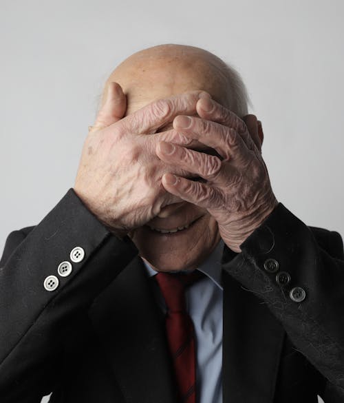 Portrait Photo De L'homme En Veste De Costume Noir Couvrant Son Visage Avec Ses Mains