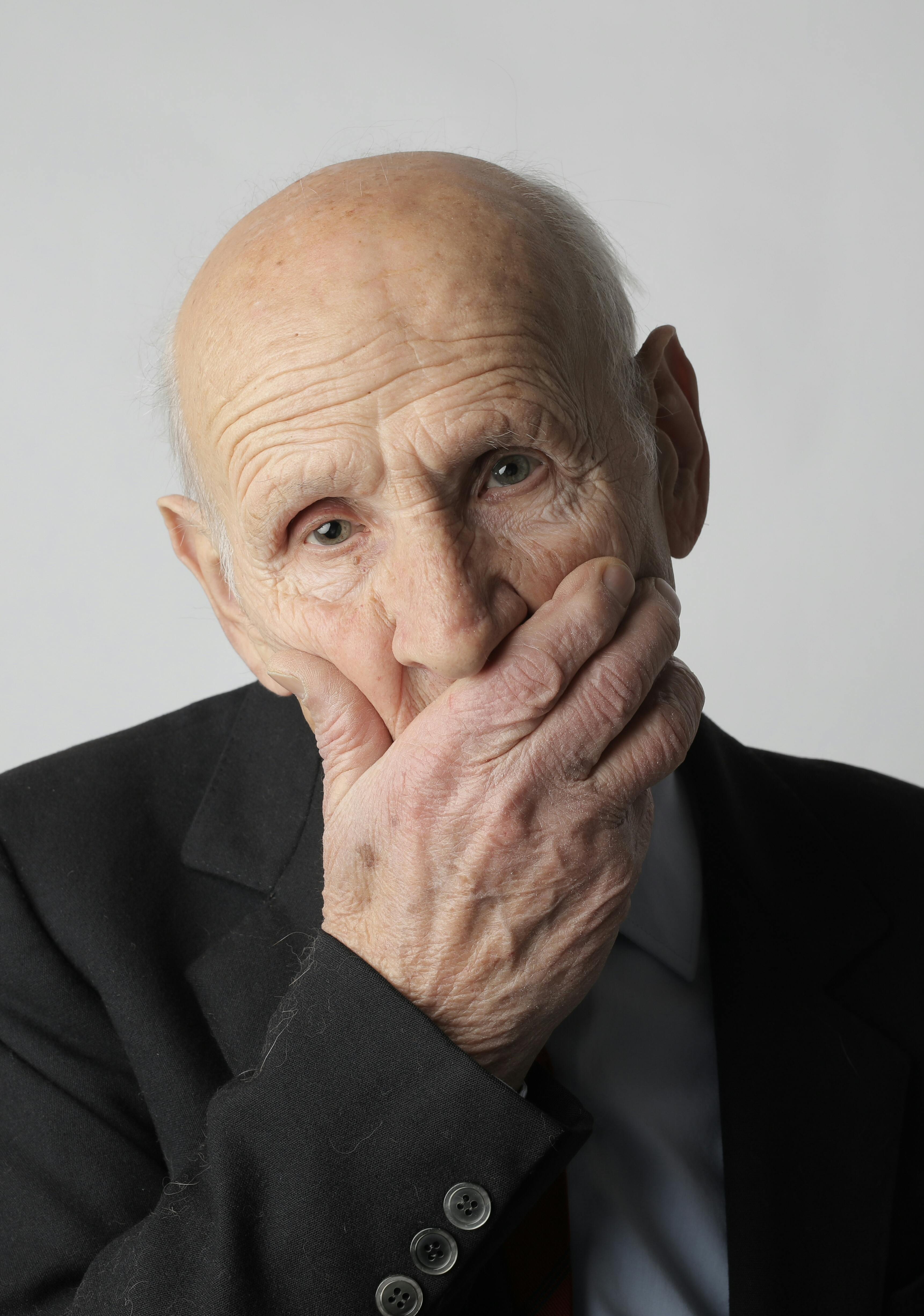 man in black suit covering his face