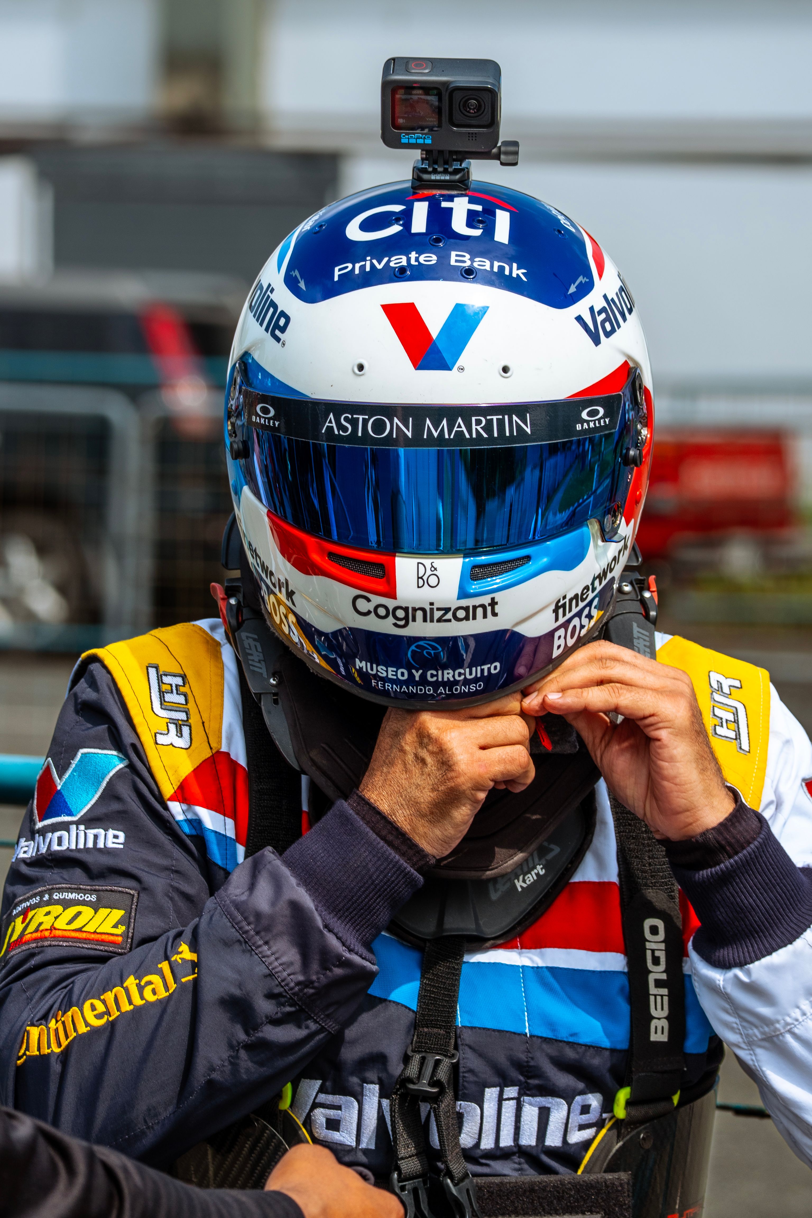 A racing driver in gear adjusts helmet before the race for better safety.