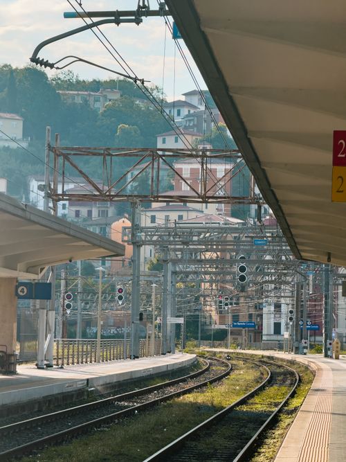 Free Quiet railway station with tracks leading into a vibrant urban landscape on a sunny day. Stock Photo
