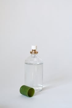 Elegant glass perfume bottle with a green cap on a light backdrop, showcasing simplicity.