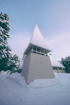 白色创意三角形塔位于冬季乡村雪谷中舒适小屋的旁边