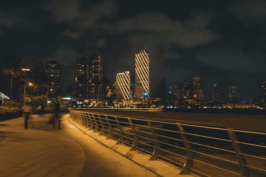 A stunning view of Colombo's skyline at night, featuring illuminated skyscrapers and a serene riverside walkway.