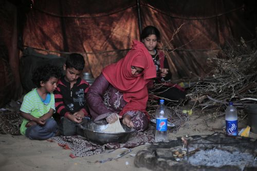 Free A family preparing food together in a traditional tent setup, depicting daily life. Stock Photo