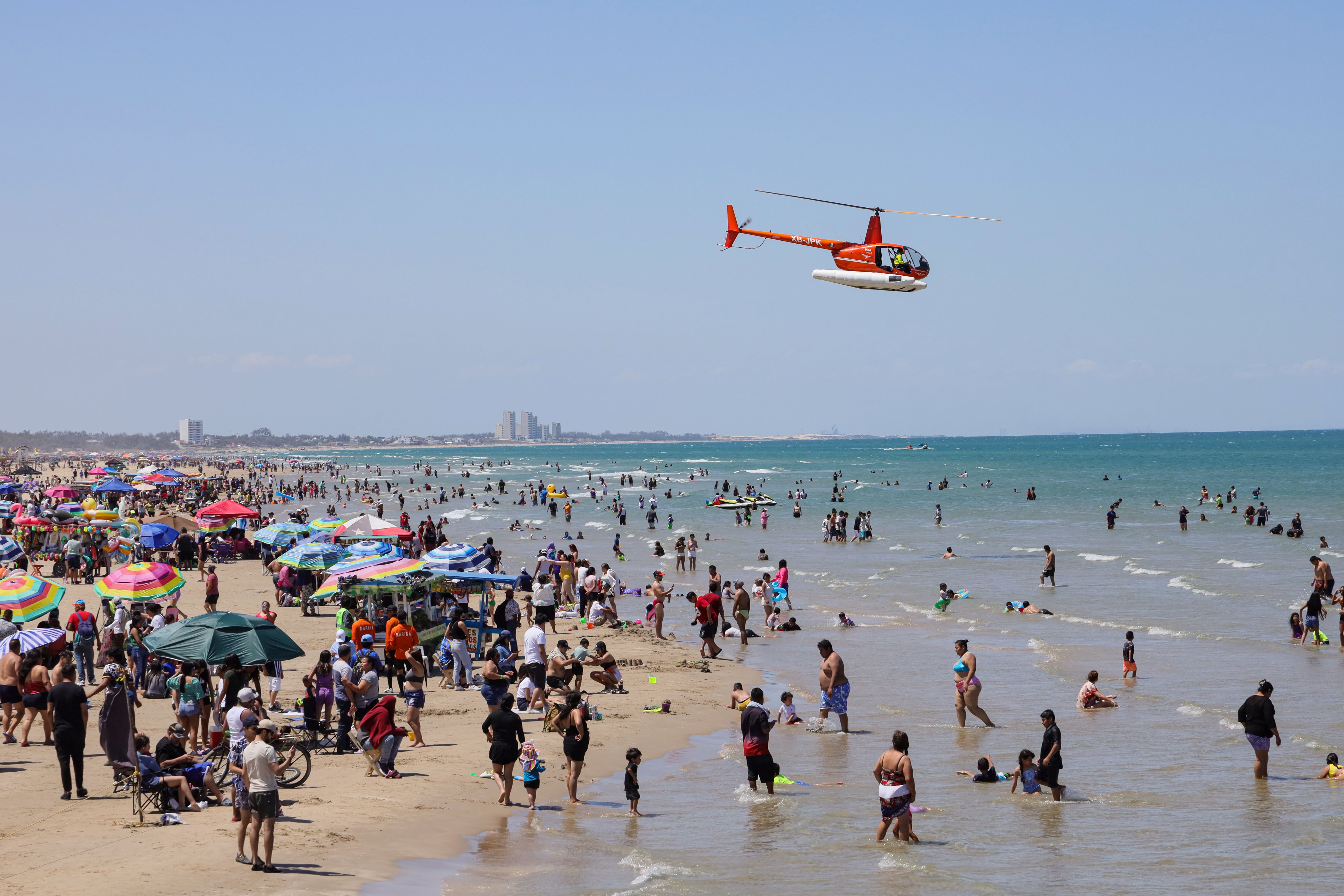 family funday north coast — A lively day at Miramar Beach, Ciudad Madero, Mexico with a helicopter flying over beachgoers.