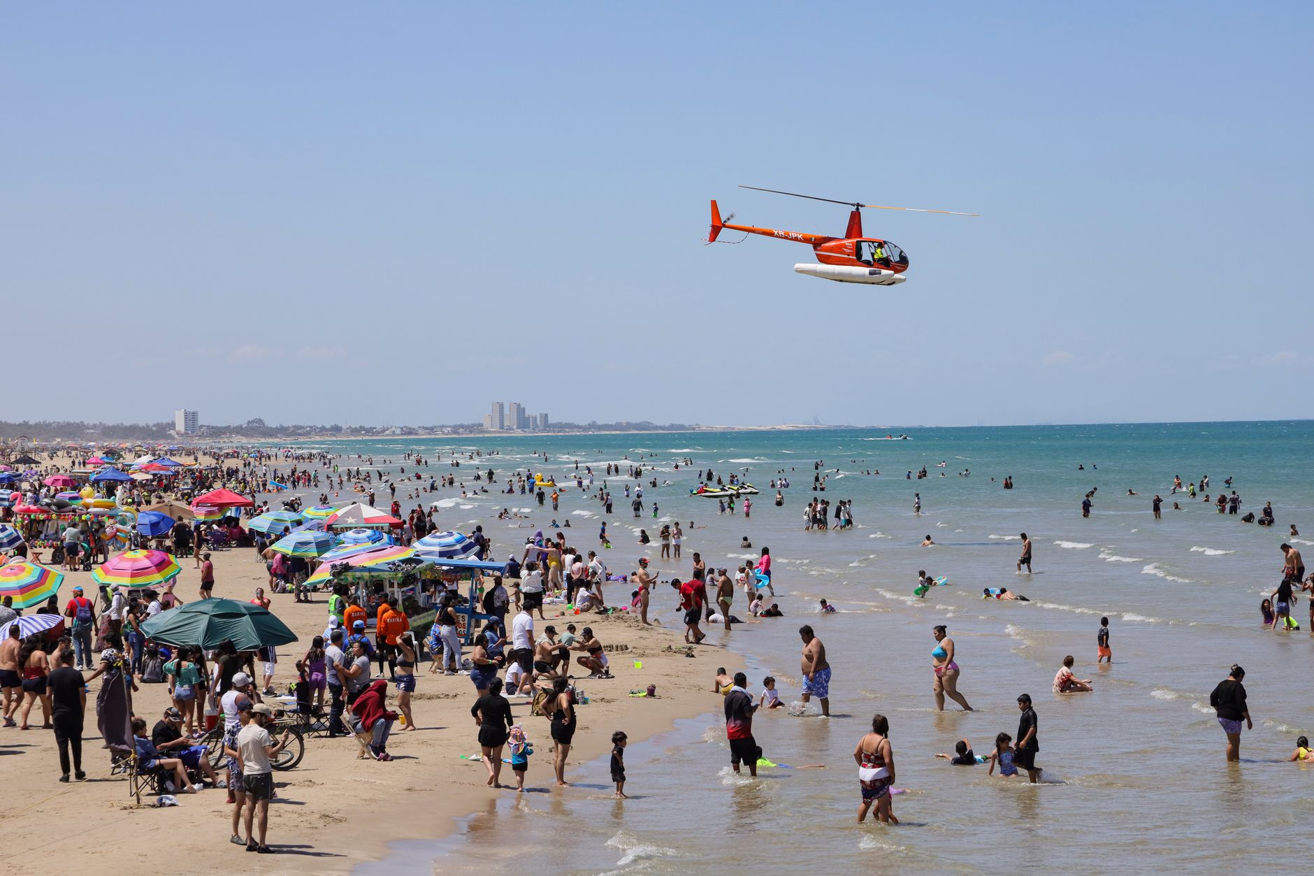 family funday north coast — A lively day at Miramar Beach, Ciudad Madero, Mexico with a helicopter flying over beachgoers.