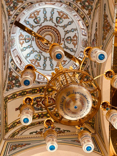 Free Intricate design of a chandelier and painted ceiling in a mosque in Medina, showcasing Islamic art. Stock Photo